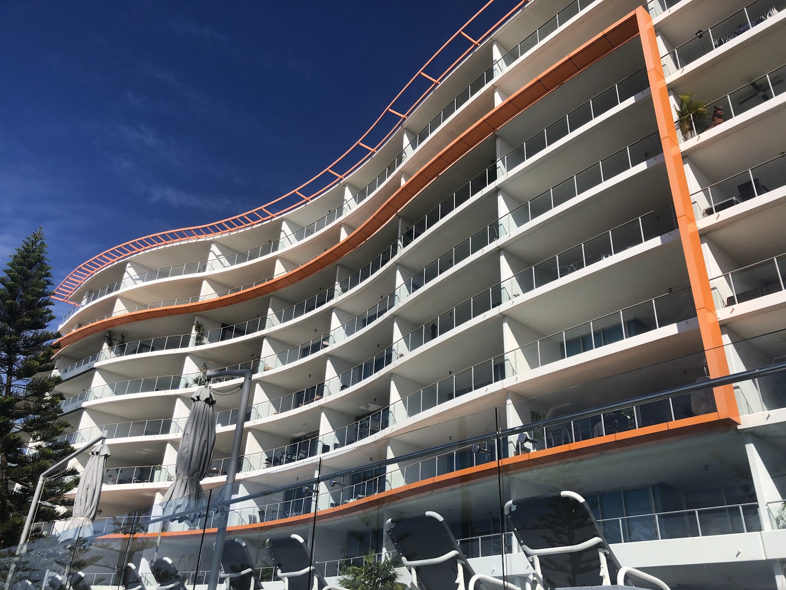 Beachfront apartment block with curved balconies under blue sky