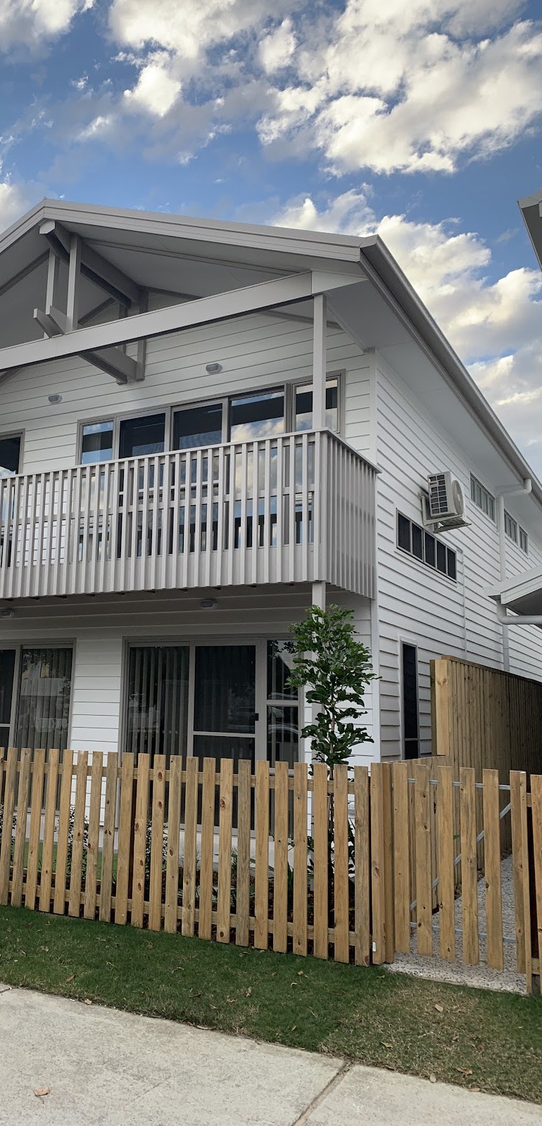 Two-storey white weatherboard house with a timber picket fence