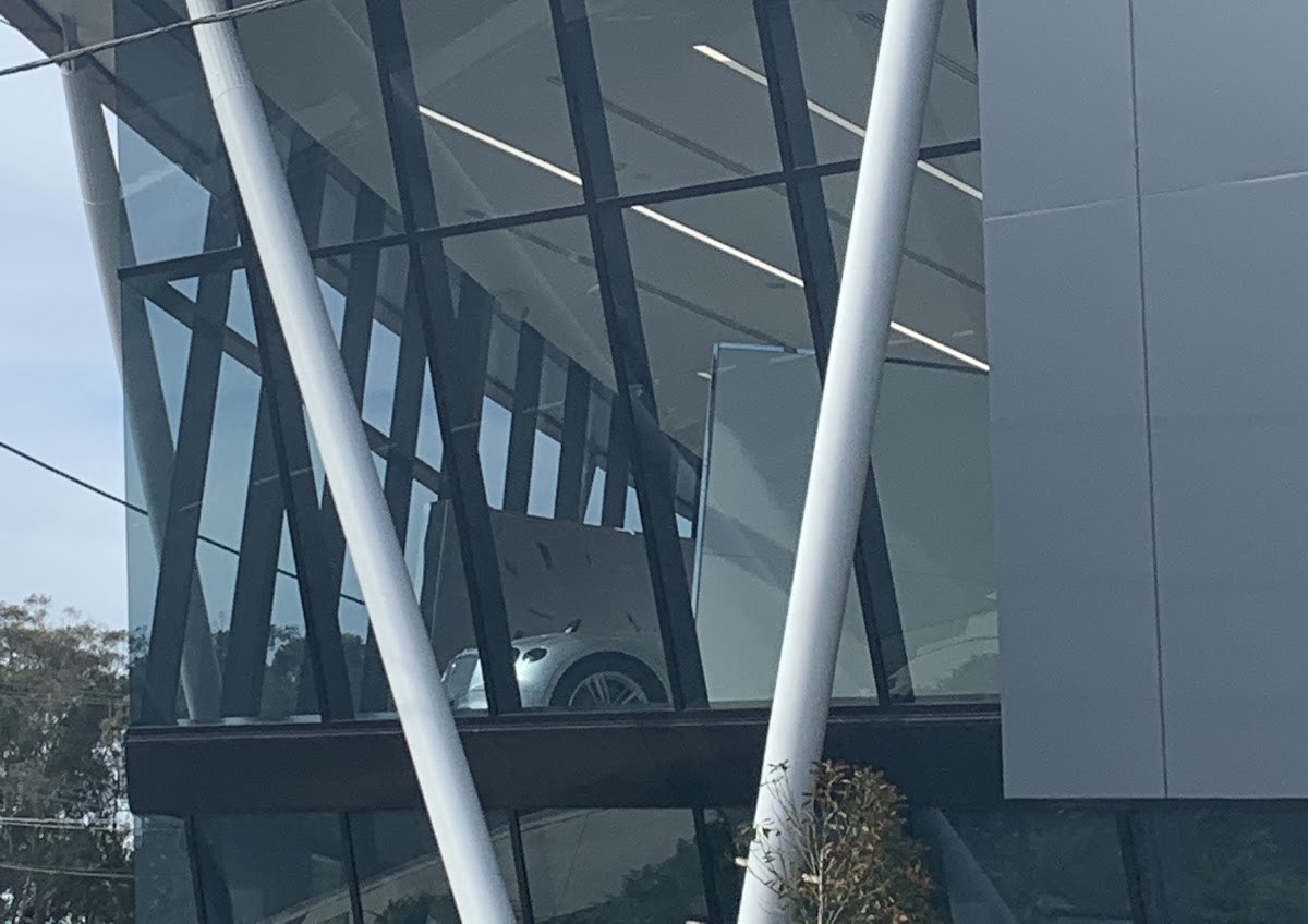 Angled glass facade of a car showroom with white steel columns